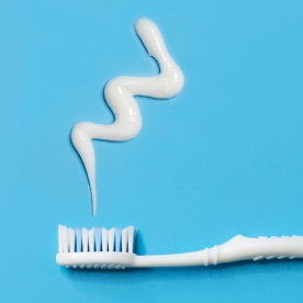 Flat lay white toothbrush and tooth paste on blue background.