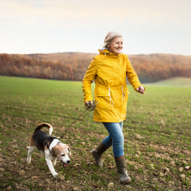Senior woman with dog on a walk in an autumn nature.