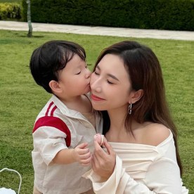 Jasmine Yongs son kisses her on the cheek on a picnic blanket outside 