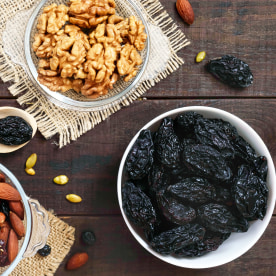Many different nuts, dried berries, prunes, pumpkin seeds in bowls.