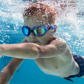 Portrait of little boy swimming underwater in the pool.