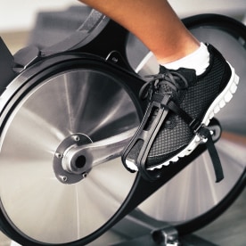Closeup of shoes on indoor stationary bike machine at home.