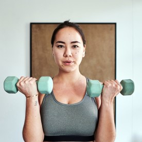 Shot of a young woman working out with weights at home.