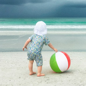 A baby is looking off into the sea at a storm coming in.