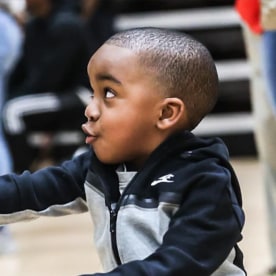 Chris Bess' son crouching at basketball game. Chris Bess' son gesturing with clipboard.