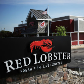 An American flag flies past Red Lobster signage displayed outside of a restaurant