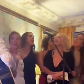 The Spice Girls in cocktail attire sing in as a man strums a guitar.