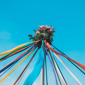 Maypole with flowers on top against a blue sky.