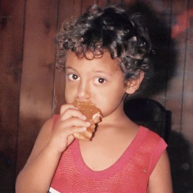 A young Steven Romo eating a donut and looking into the camera