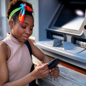 Young woman withdrawing money from credit card at ATM.