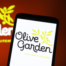 Olive Garden logo is seen on a smartphone and in the background.