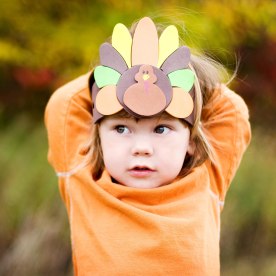 A girl wearing a Thanksgiving turkey headdress