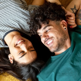 Happy young Caucasian couple laying on the floor.