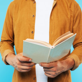 cropped image of man holding open book isolated on blue