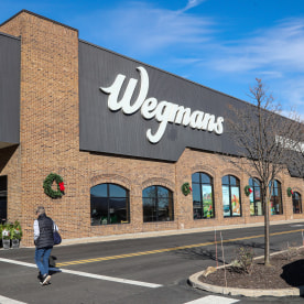 A woman is seen approaching the entrance of a Wegmans