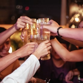 Group of young people hands toasting and cheering beers.