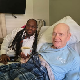 Donell Stallworth brings Charlie Hicks a cup of gumbo at the hospital.