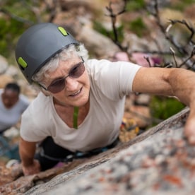 Healthy senior woman rock climbing on the cliff
