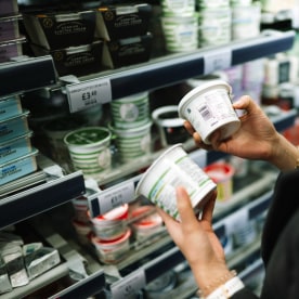 Close-up of shopper comparing nutritional labels on food packaging.