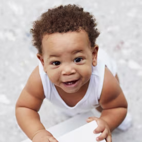 Overhead view of smiling baby boy standing in kitchen