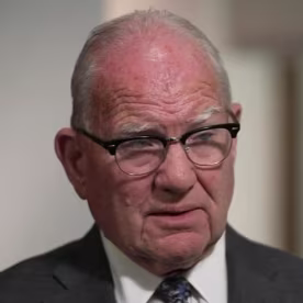 Image: A man in glasses and a suit.