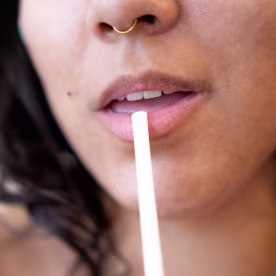 Young woman drinking with straw, close-up