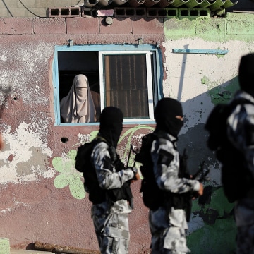 A woman watches fighters of the Ezz Al-Din Al Qassam Brigades, the armed wing of the Palestinian Hamas movement, march during a military parade in northern Gaza City on Sept. 10, 2016. (Photo by Mohammed Saber/EPA)