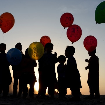 Afghan children hold their balloons at sunset on the outskirts of Herat, Afghanistan on Oct. 28, 2016. (Photo by Aref Karimi/AFP/Getty)