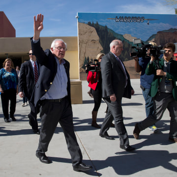 Image: Sanders waves to voters as he leaves a caucus site