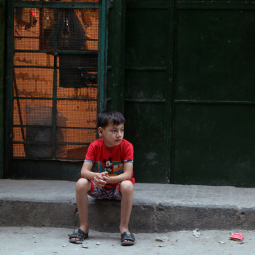 Image: A boy sits outside a bakery in the rebel held al-Shaar neighbourhood of Alepp