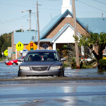 Image: A car navigates a flooded street off Highway 41 in Lumberton