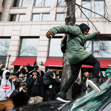 Image: A protester kicks in a windshield during a demonstration in Washington, D.C on Jan. 20 after the inauguration of President Donald Trump.