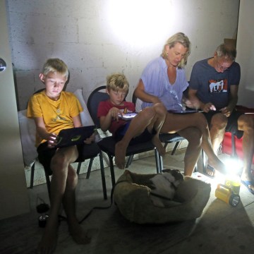 Image: The Blinckman family use their personal devices while sheltering in a stairwell utility closet as Hurricane Irma goes over Key West on Sept. 10.