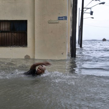 Image: A man swims on a flooded street in Havana