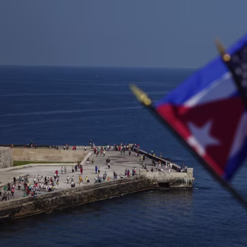 Image: Passengers on board Carnival's Adonia cruise ship wave flags as they arrive from Miami in Havana