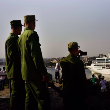 Image: Cuban soldiers watch the Carnival Adonia cruise ship arrive from Miami