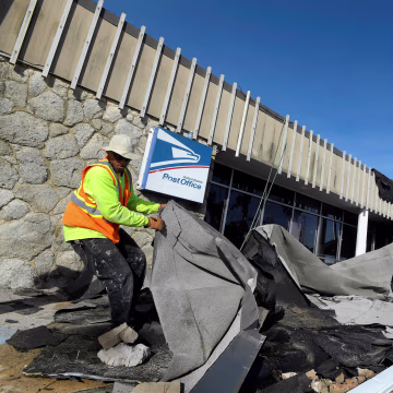 Image: Jordan Mays removes the roof that blew off of a U.S. Post Office location in the aftermath of Hurricane Matthew in Daytona Beach