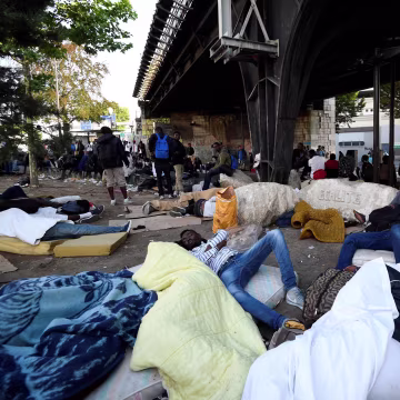 Image: Migrants and refugees rest on the ground