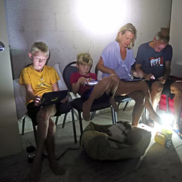 Image: The Blinckman family use their personal devices while sheltering in a stairwell utility closet as Hurricane Irma goes over Key West on Sept. 10.