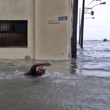 Image: A man swims on a flooded street in Havana