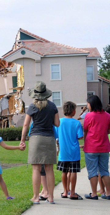 Image: People look at a partially collapsed building over a sinkhole at Summer Bay Resort near Disney World .