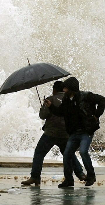 Image: Lebanese men react as waves crash into a