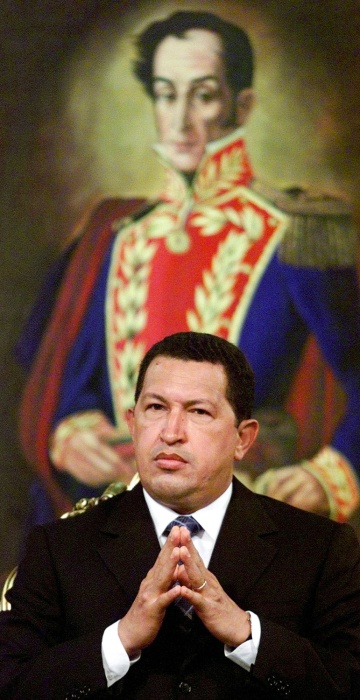 Image: Venezuelan President Hugo Chavez sits in front of a painting of the country's liberation hero Simon ..