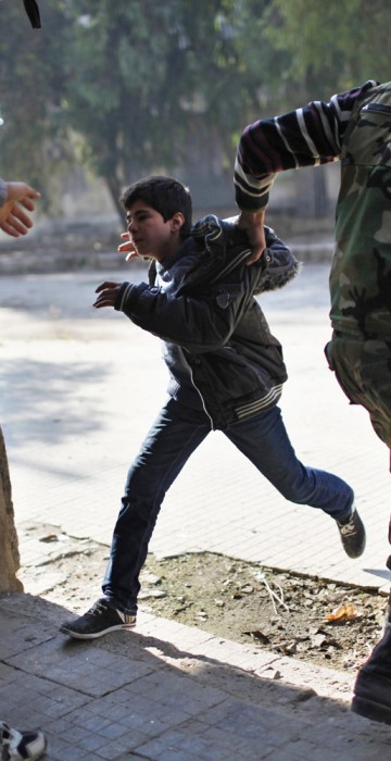 Image: A Free Syrian Army fighter pulls a boy off the street as a sniper fires during fighting with forces loyal to Syrian President Bashar el-Assad in Aleppo city
