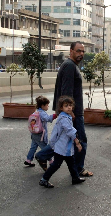 Image: A man and his children walk away from clashes between Sunni Muslim gunmen and members of the Lebanese army in Kaskas, Beirut