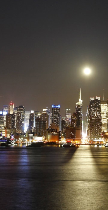 Image: Image: A full moon rises over New York City above 42nd Street, as seen across the Hudson River in Weehawken, New Jersey