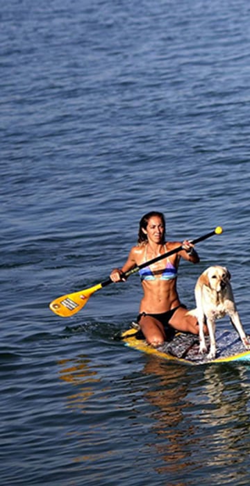 Image: A woman paddles with her  dog at Arpoador beach in Rio de Janeiro