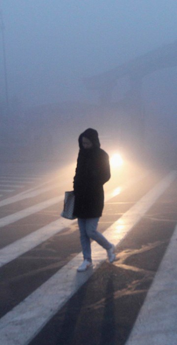 Image: A woman walks along a street during a smoggy day in Changchun