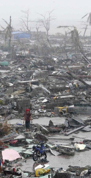 Image: Survivors stand among debris and ruins of houses destroyed after Super Typhoon Haiyan battered Tacloban city in central Philippines