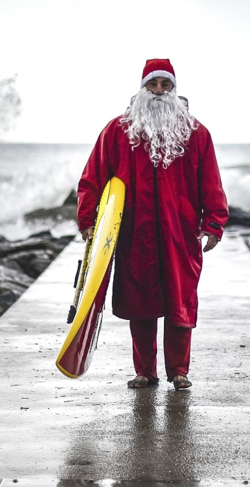 TOPSHOT - Italian SUP (Stand up Paddle) surfer Federico Piccinaglia dressed as Santa Claus poses with his board on December 1, 2015 in Levanto, near La Spezia. AFP PHOTO / OLIVIER MORIN / AFP / OLIVIER MORINOLIVIER MORIN/AFP/Getty Images